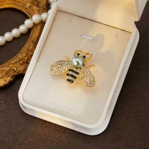 Exquisite bee brooch detail featuring shining rhinestones and pearl presented in a jewelry box.