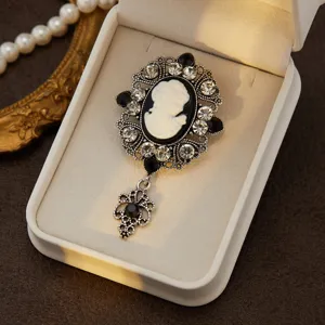 Vintage cameo brooch with silver filigree setting, sparkling rhinestones and elegant drop pendant.