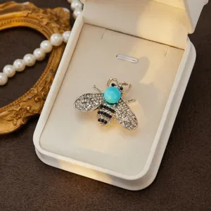 Close-up detail shot of exquisite rhinestone bee brooch with turquoise head in velvet box.