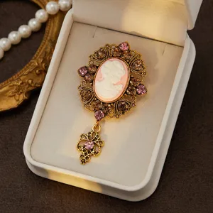 Vintage cameo brooch with ornate filigree metal frame, sparkling rhinestones and pendant charm.