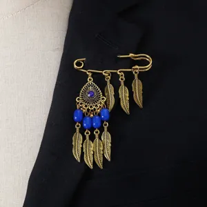 Vintage bohemian style golden safety pin brooch with blue beads and feather charms.
