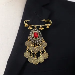 Broche dorada vintage con pedrería roja en el centro y dijes de monedas colgantes detalle.