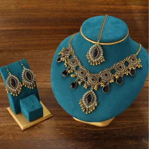 Gros plan sur l'ensemble de bijoux ethniques vintage avec collier, boucles et bijou de tête.