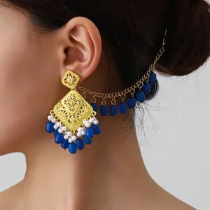 Detail view of ethnic vintage carved metal earrings with blue beads, pearls and chain.