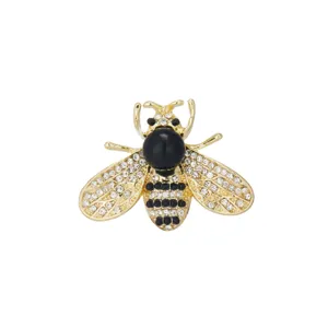 Close up view of exquisite crystal rhinestone bee brooch detail, elegant gold tone metal.