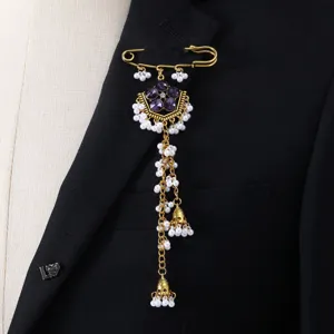 Close-up of vintage ethnic rhinestone brooch with delicate white pearl long tassels and gold pin.