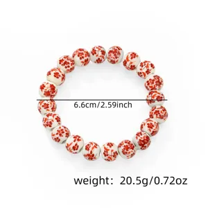 Detail view of Chinese style ceramic bead bracelet featuring red floral pattern and smooth finish.