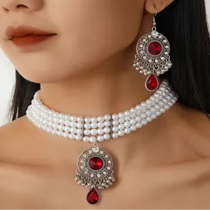 Detailed close-up of vintage ethnic faux pearl choker necklace with ornate red gem pendant.