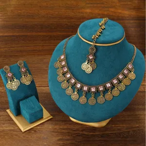 Detailed view of bohemian ethnic coin necklace earrings set with pink gemstone accents.