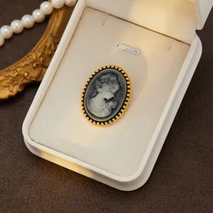 Detailed shot of a vintage cameo brooch in a white box, elegant palace style for women's fashion.