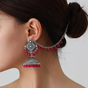 Nahaufnahme der böhmischen indischen gravierten Silberjhumka-Ohrringe mit rosa Perlen.