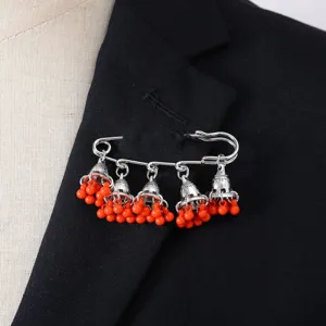 Close-up detail of bohemian vintage bell tassel brooch featuring bright orange beads on black suit.