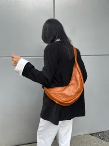 Détail de sac souple marron en cuir, forme croissant élégante pour usage quotidien.