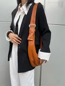 Gros plan sur le sac souple en cuir marron, mettant en valeur la texture et les boucles.