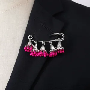 Close-up of bohemian silver-tone bell tassel brooch with hot pink beads on suit lapel.