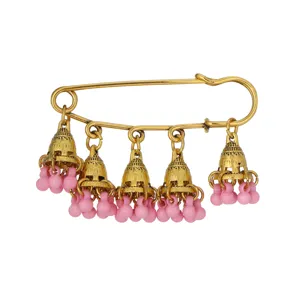 Vintage gold-toned safety pin brooch detail, featuring hanging bell charms with pink beads.