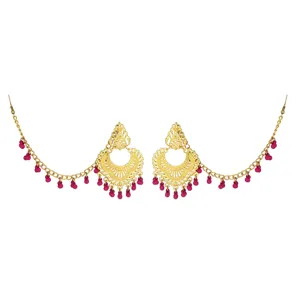 Detail shot of vintage gold-toned ethnic earrings with intricate carvings and pink beaded tassels.