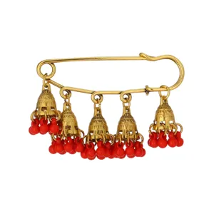 Detailed shot of a vintage gold safety pin brooch with hanging bell charms and red beads.