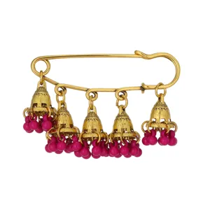 Close-up of antique gold safety pin brooch with hanging jhumka bells and pink bead details.