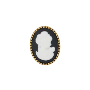 Close-up of a vintage cameo brooch with a classic black and white silhouette and gold beaded trim.
