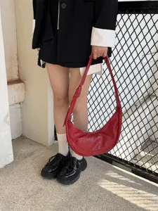 Vue de détail du sac porté épaule souple en cuir rouge mettant en valeur sa forme de croissant.