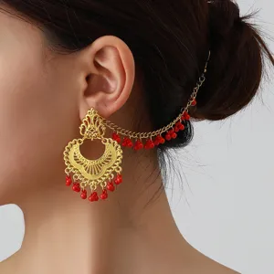 Detail shot of vintage Indian style gold-plated ear chain with red bead fringe, ethnic.