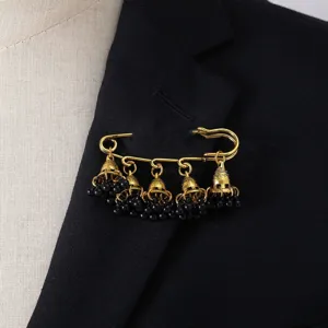 Vintage gold safety pin brooch featuring bohemian bell tassels and black beads, elegant detail shot.