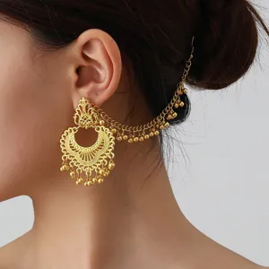 Detailed shot of ethnic carved ear chain and retro tassel earrings, vintage gold tone style.