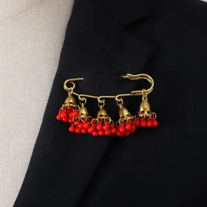 Vintage gold tone jhumka tassel brooch pin with red beads for elegant women fashion detail.