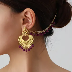 Close-up detail shot of vintage ethnic gold-toned hollow carved earrings with purple bead ear chain.