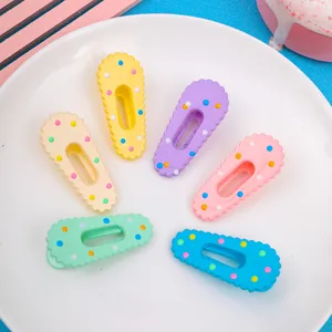 Close-up detail of cute colorful polka dot acrylic candy hair clips arranged on white plate.