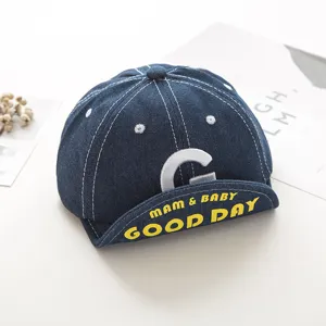 Detailed close-up of baby denim baseball cap showing white stitching and embroidered letter.