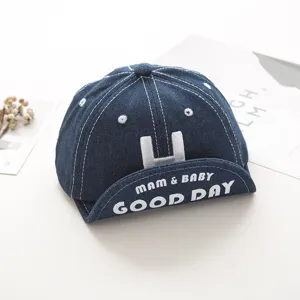 Infant denim baseball cap detail view, embroidered letter H and brim text design, soft fabric.