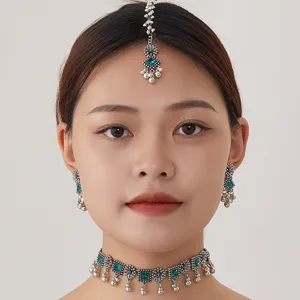 Detailed close-up of ethnic silver jewelry set featuring intricate metalwork and green crystal.
