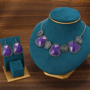 Detailed shot of retro purple stone necklace and earrings set with silver textured metal.