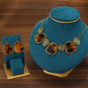 Retro tortoise shell necklace earrings set detail, vintage gold textured fashion jewelry display.