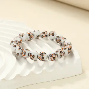 Close-up shot of white ceramic bead bracelet with delicate black and orange floral patterns.