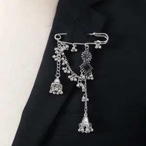 Close-up detail of vintage silver bohemian tassel safety pin brooch with bells and black stone.
