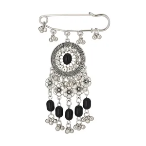 Dettaglio ravvicinato di spilla etnica vintage in argento con nappe e cristalli brillanti.