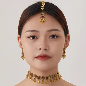 Detail shot of bohemian ethnic gold choker necklace, earrings and maang tikka jewelry set.