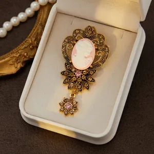 Detailed view of vintage cameo rhinestone brooch with ornate gold filigree and pendant.