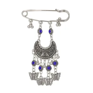 Close-up of a bohemian retro vintage metal rhinestone tassel brooch pin detail shot.