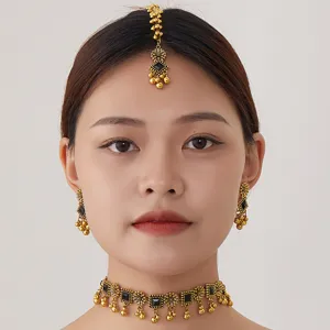 Close-up detail of ethnic bohemian gold choker necklace, earrings and tikka set with black stones.