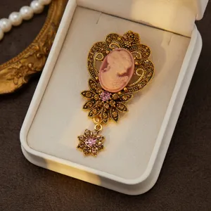 Close-up of vintage cameo rhinestone brooch detail, retro gold-tone finish and sparkling pink crystals.