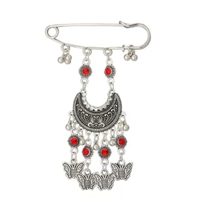 Detailed view of bohemian vintage silver brooch with red rhinestones and butterfly charms.