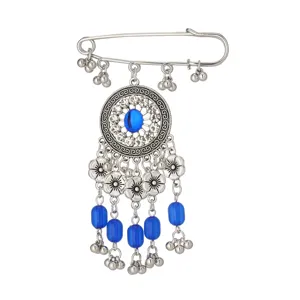 Dettaglio ravvicinato della spilla etnica con strass brillanti, perle blu e pendenti.