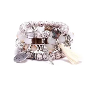 Bohemian multi-layer beaded bracelet detail featuring metal charms, wing and tassel pendants.