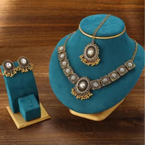 Detailed close-up view of vintage ethnic Indian rhinestone necklace and earrings set on teal velvet.