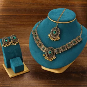 Detailed close-up view of vintage Indian green rhinestone tassel necklace and earrings set.