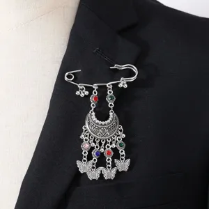 Bohemian vintage rhinestone tassel brooch detailed view, ethnic carved pin accessory.